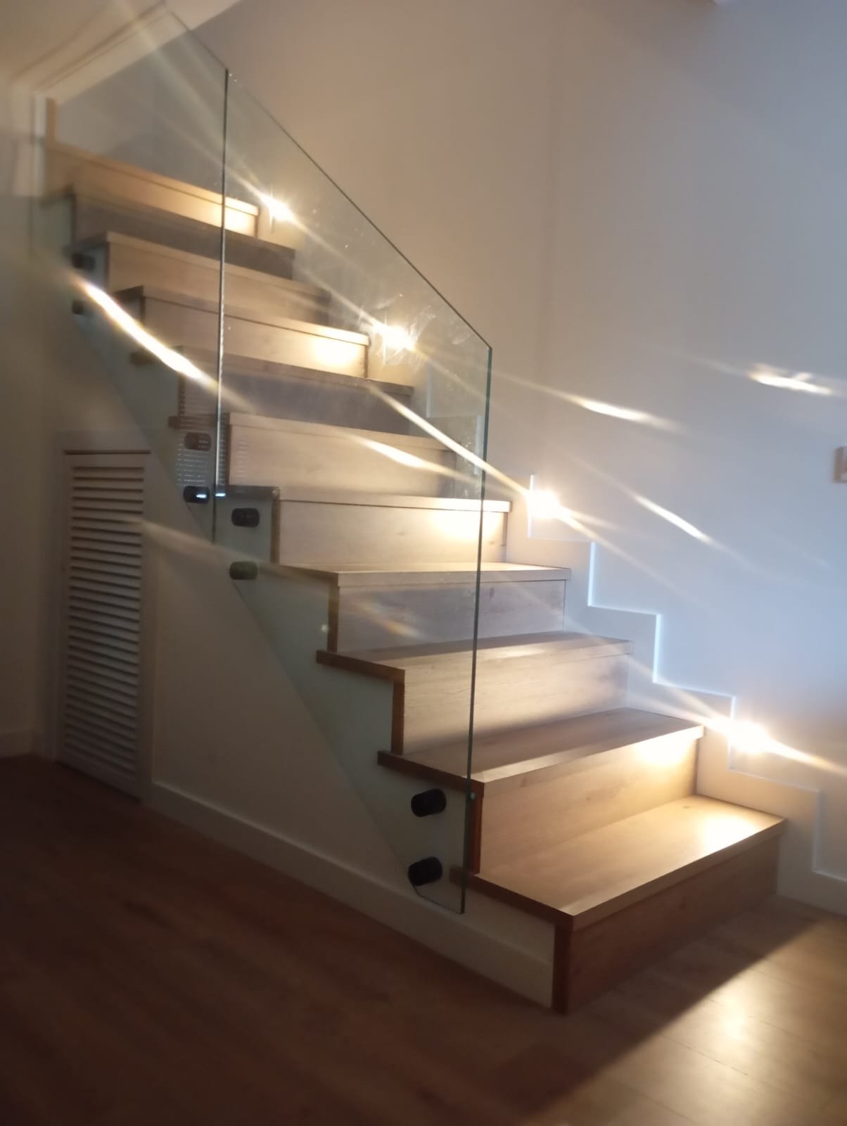Escalera revestida en madera con barandilla de cristal
